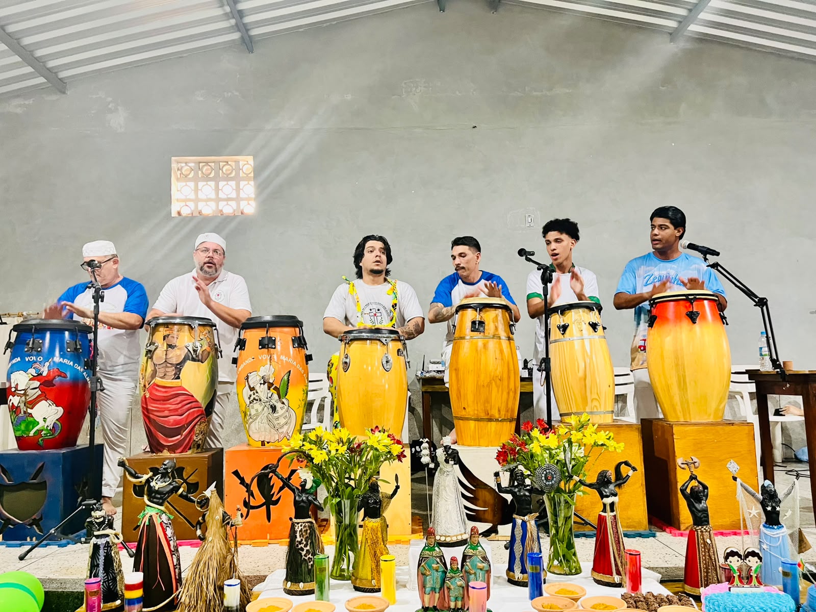 Grupo de músicos tocando atabaques durante a celebração