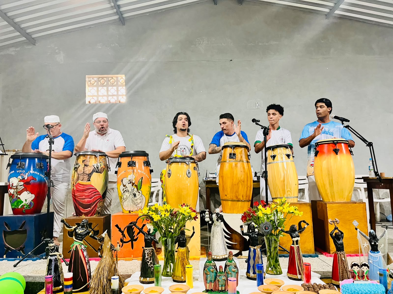 Músicos tocando atabaques diante do altar da festa